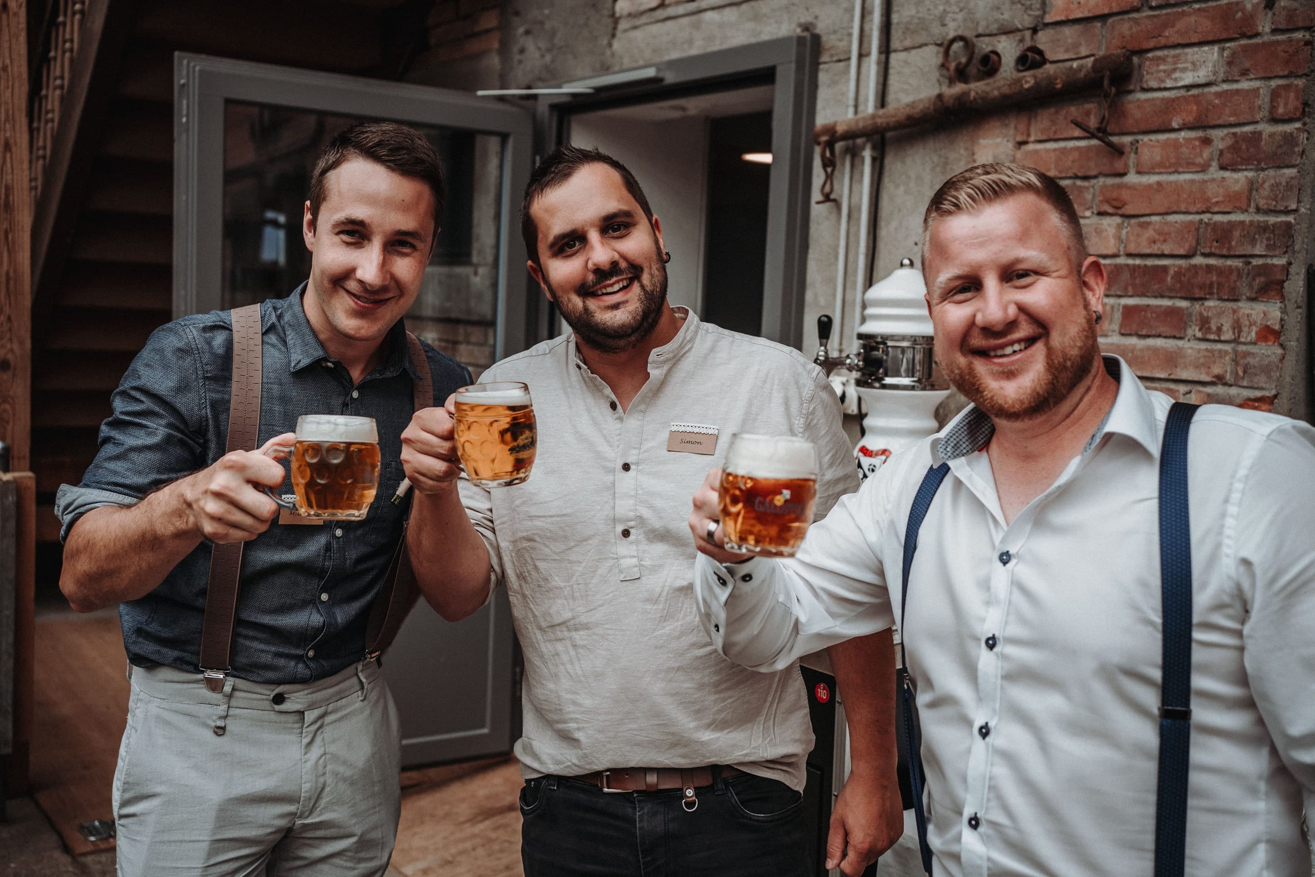 Drei Gäste stossen mit Bier an