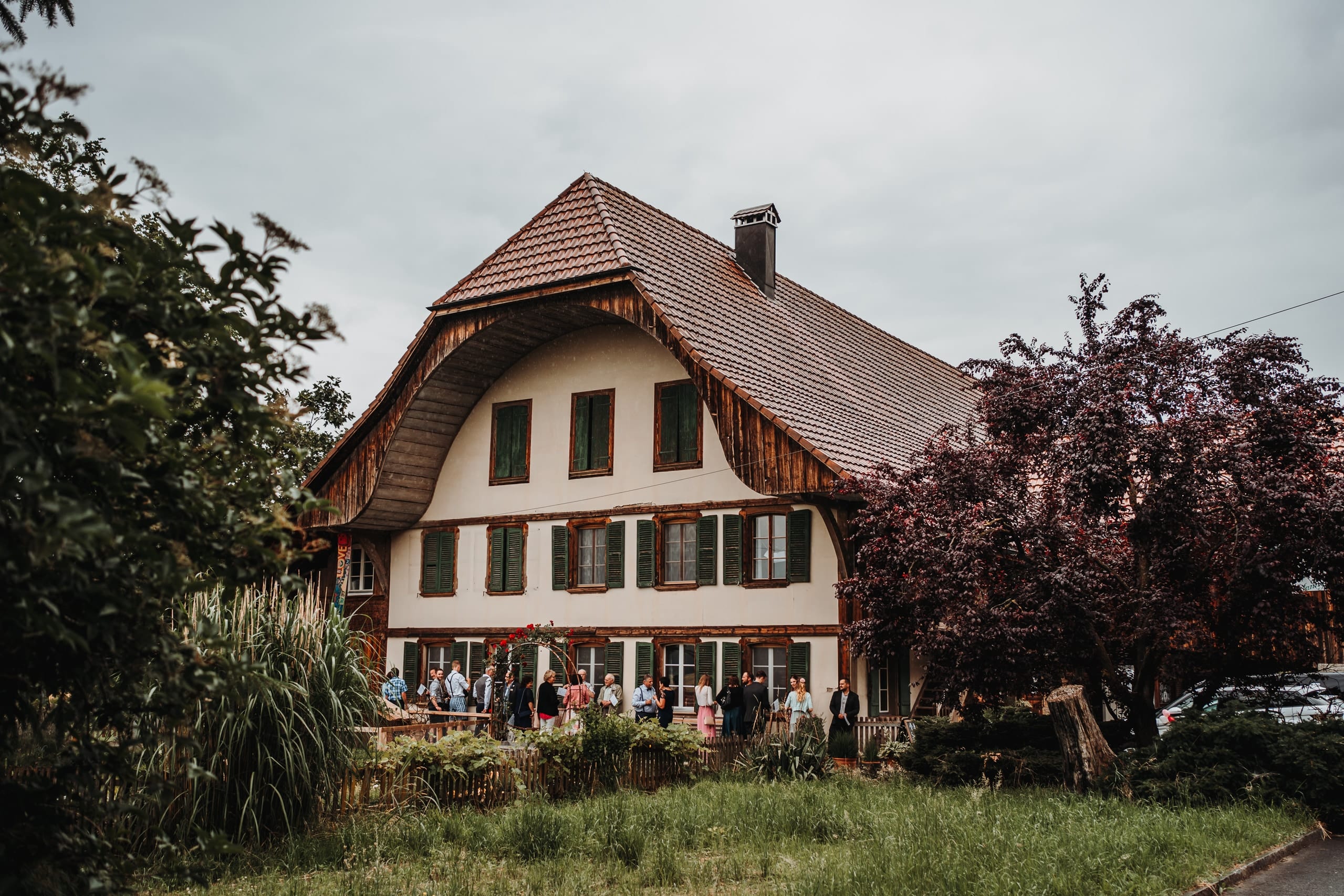 Gäste vor einem grossen Bauernhaus mit Holzgiebel