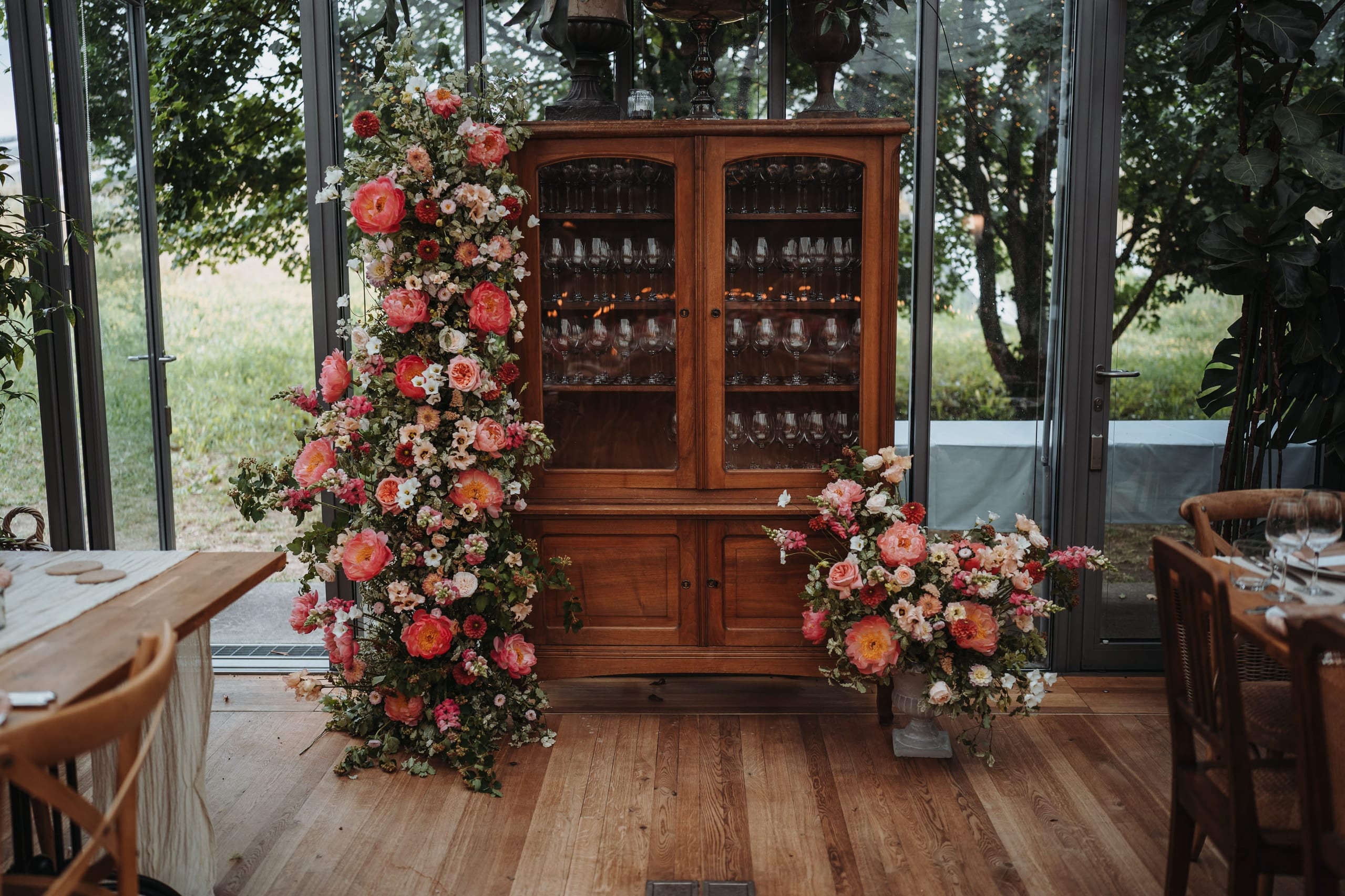 Eine Blumensäule neben einem alten Holzschrank im Hochzeitssaal