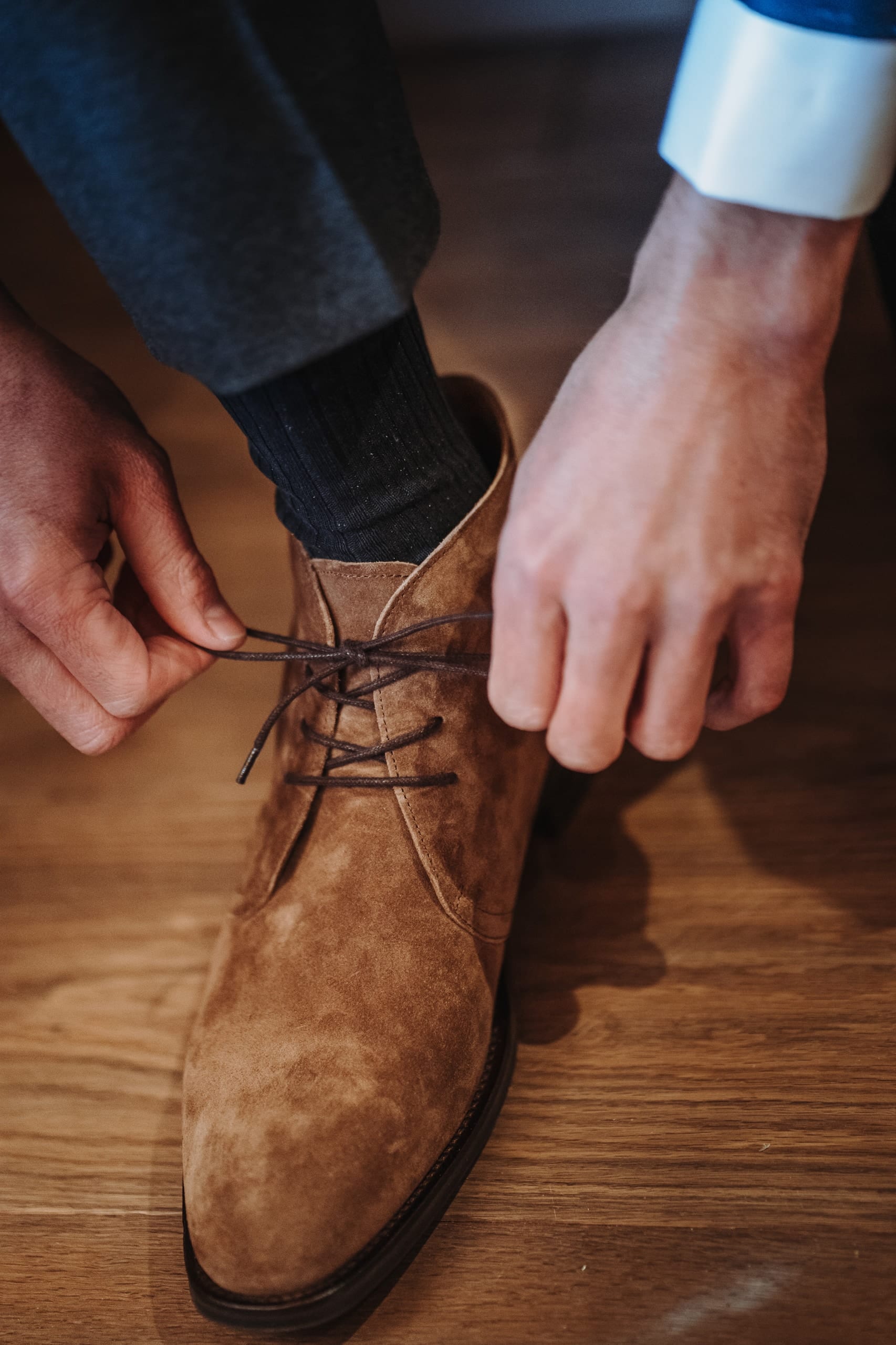 Der Bräutigam schnürt seine braunen Wildlederschuhe