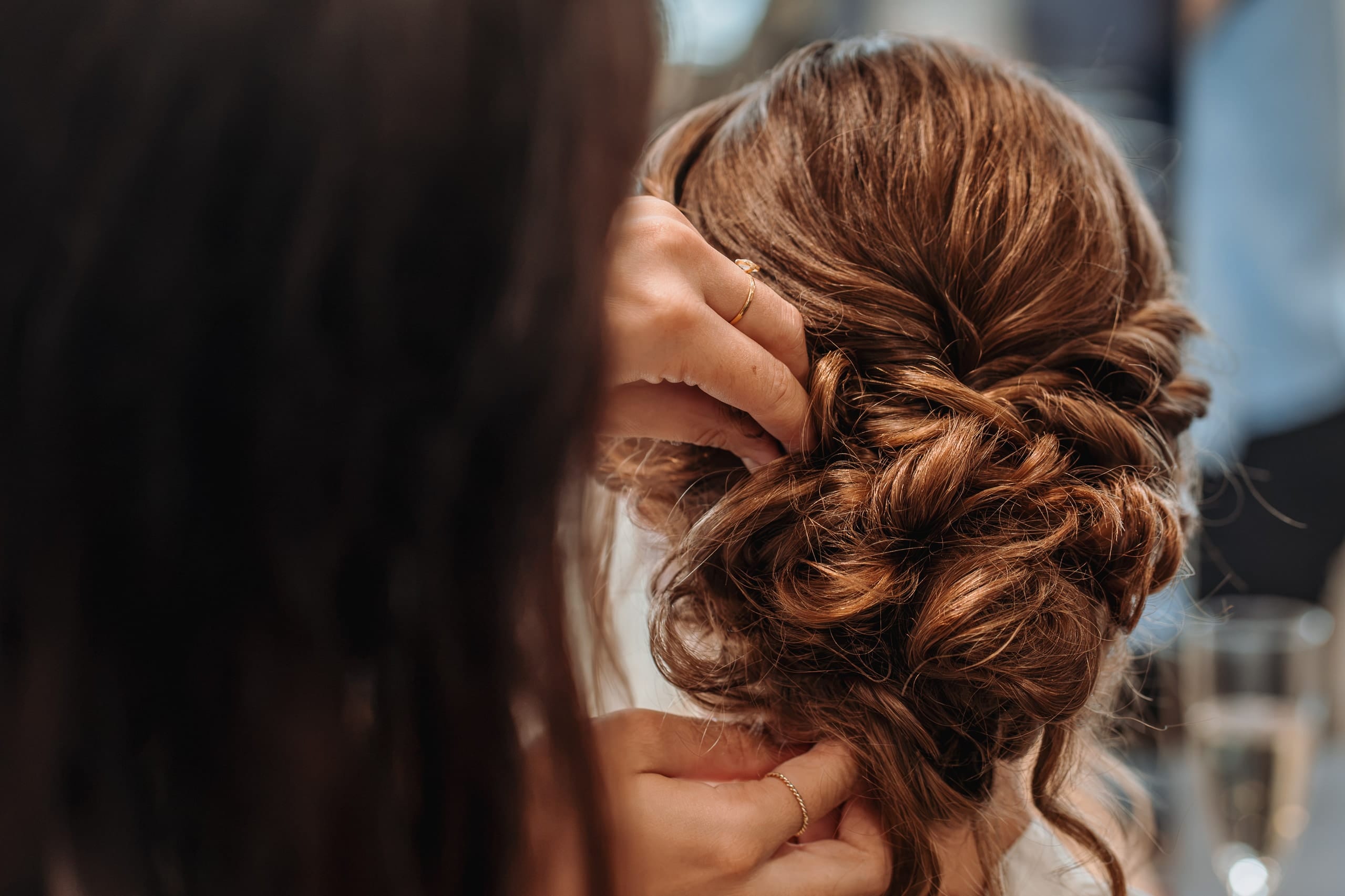 Die Coiffeuse steckt die Locken der Brautfrisur fest