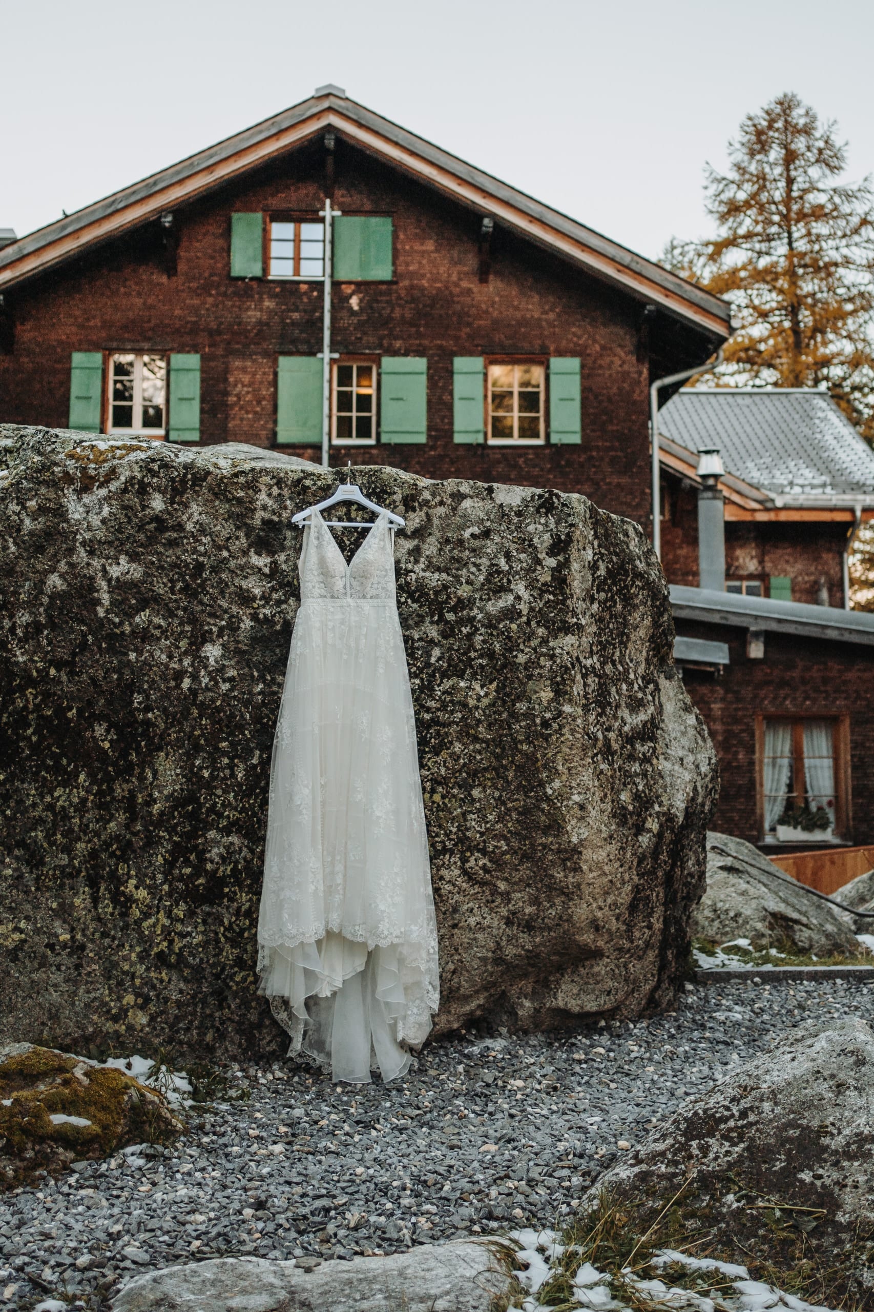 Das Brautkleid hängt an einem grossen Felsen vor dem Berghotel