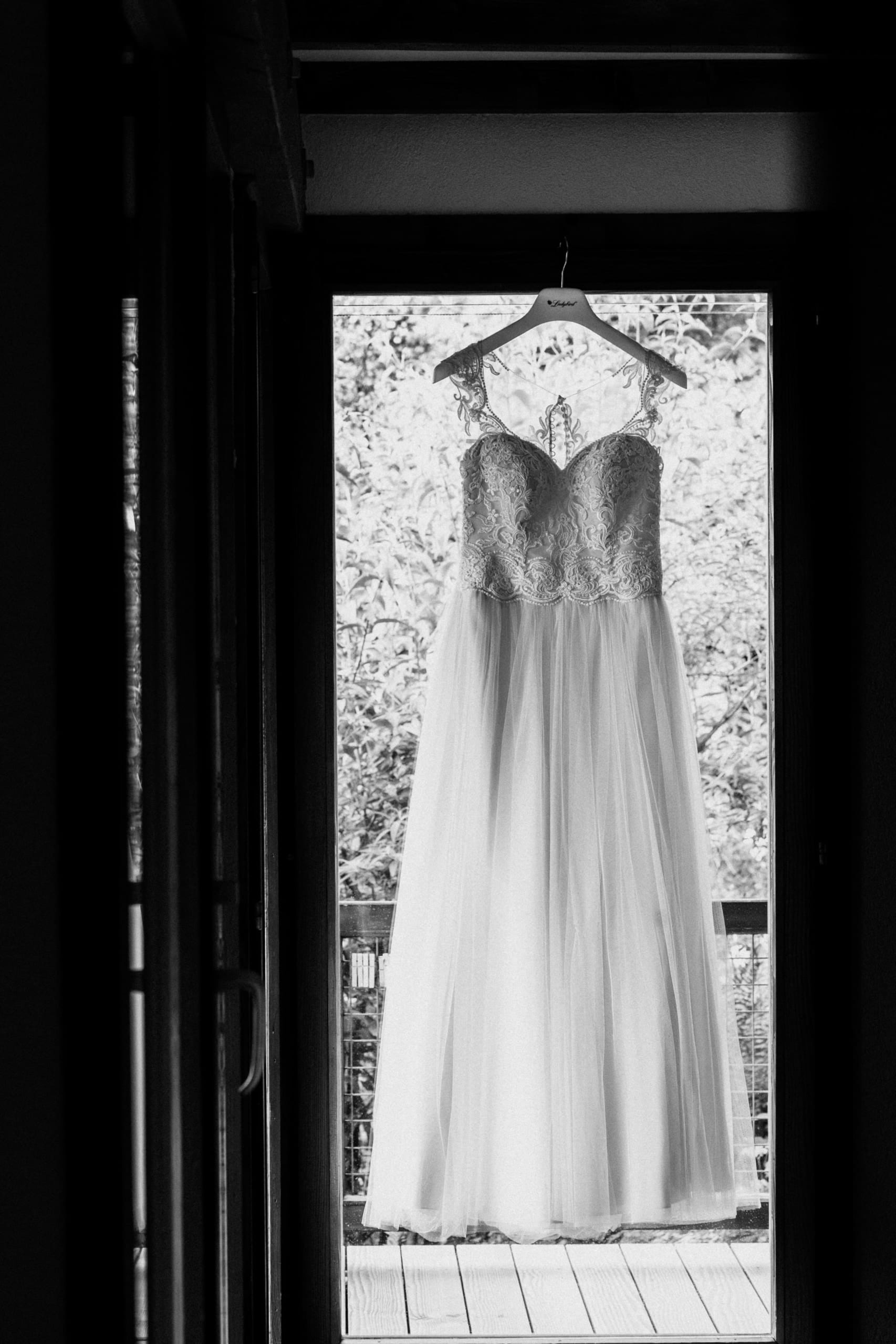 Schwarzweiss: Das Brautkleid hängt in einer offenen Tür