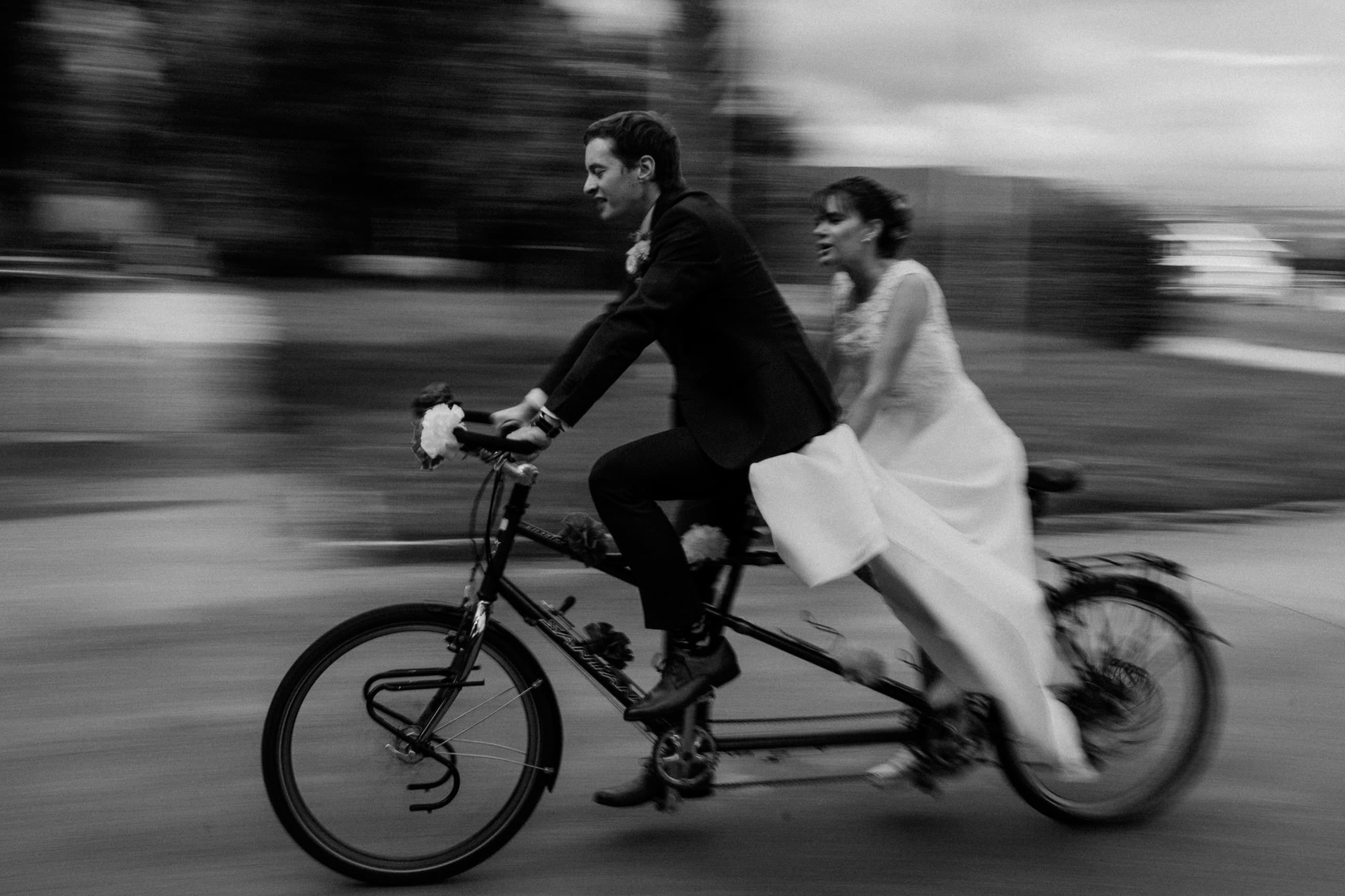 Das Brautpaar fährt auf einem Tandem vorbei, schwarz-weiss