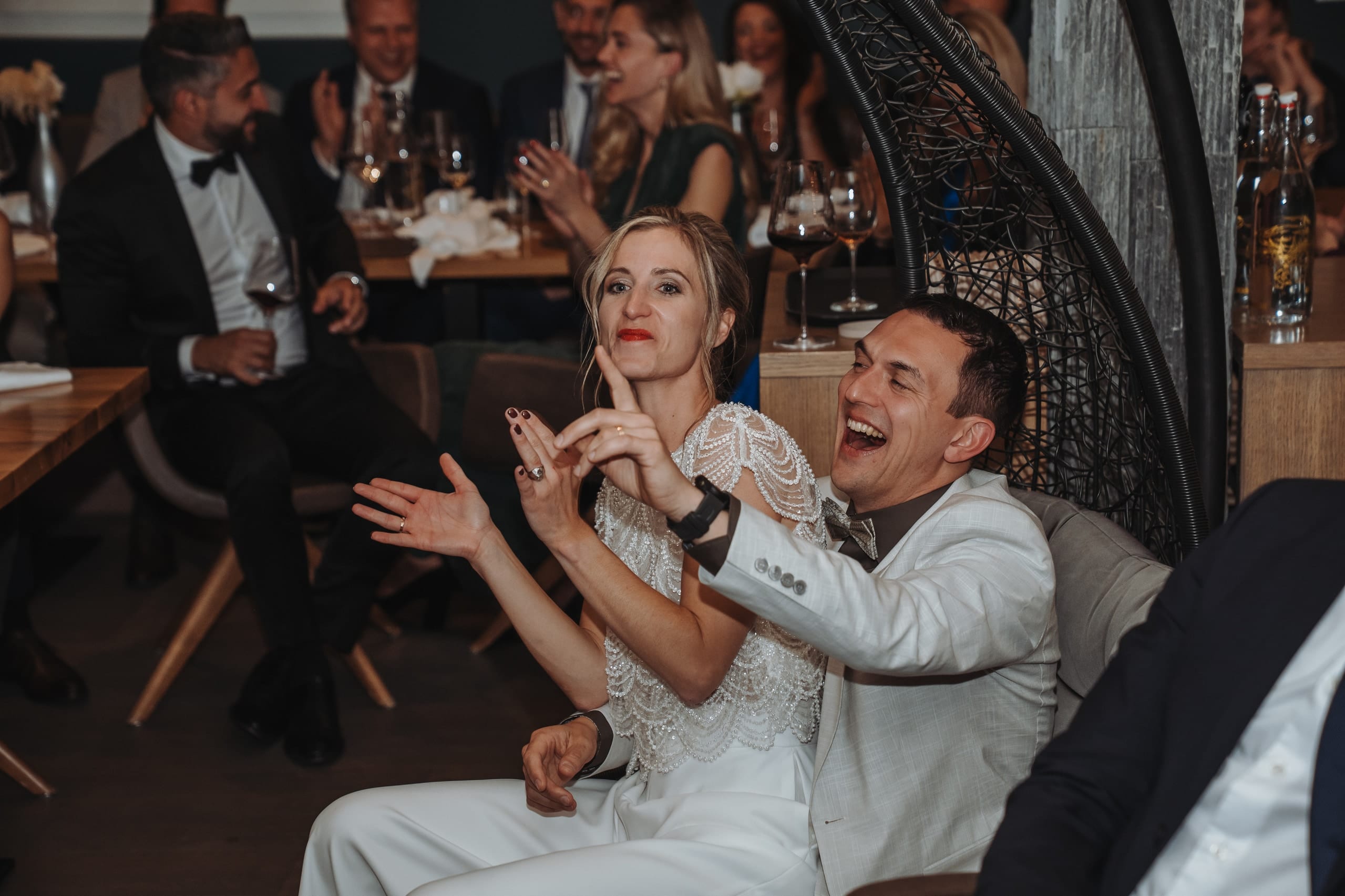 Braut und Bräutigam lachen und gestikulieren am Tisch