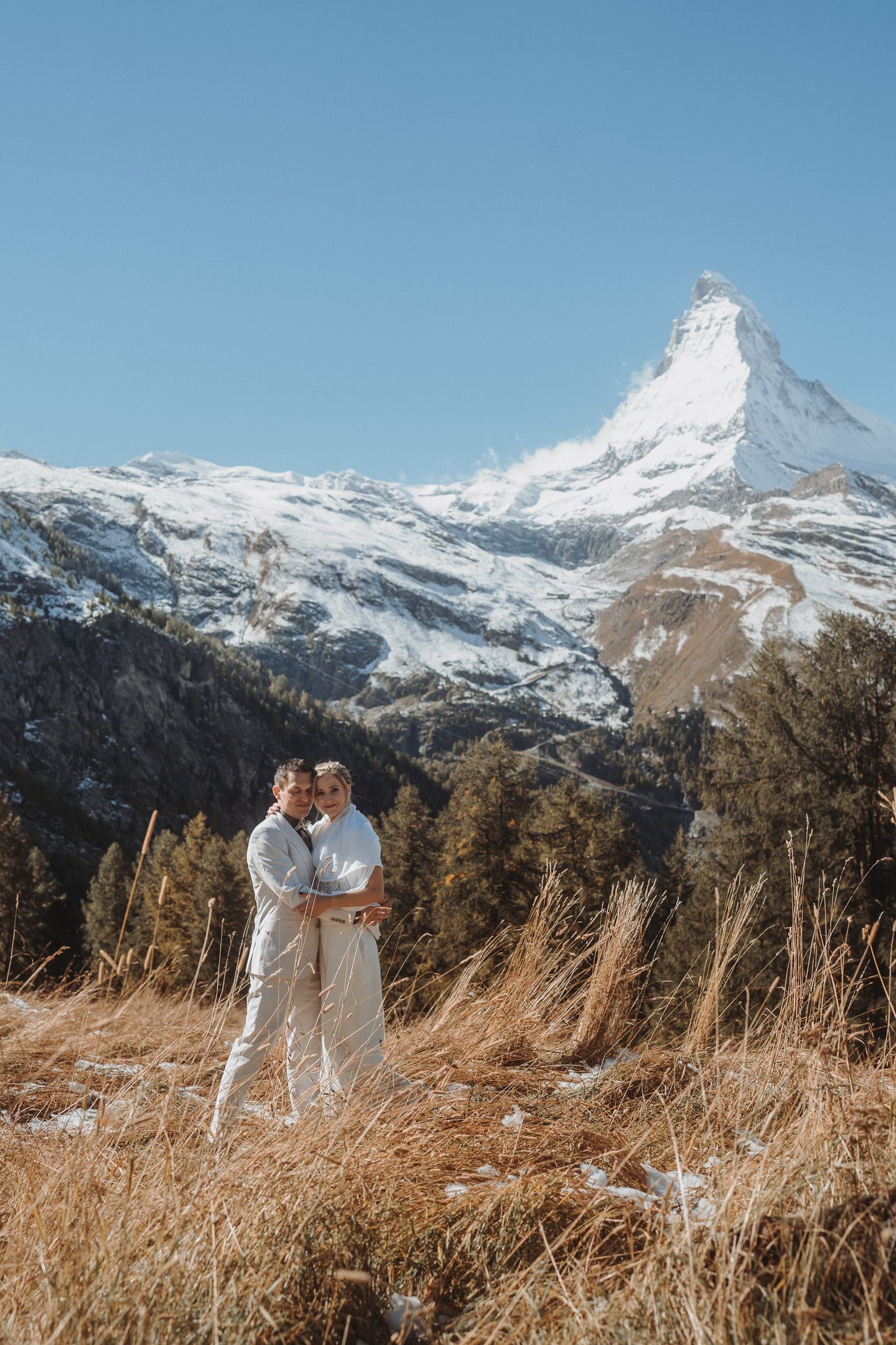 Das Brautpaar umarmt sich im hohen Herbstgras vor dem Matterhorn