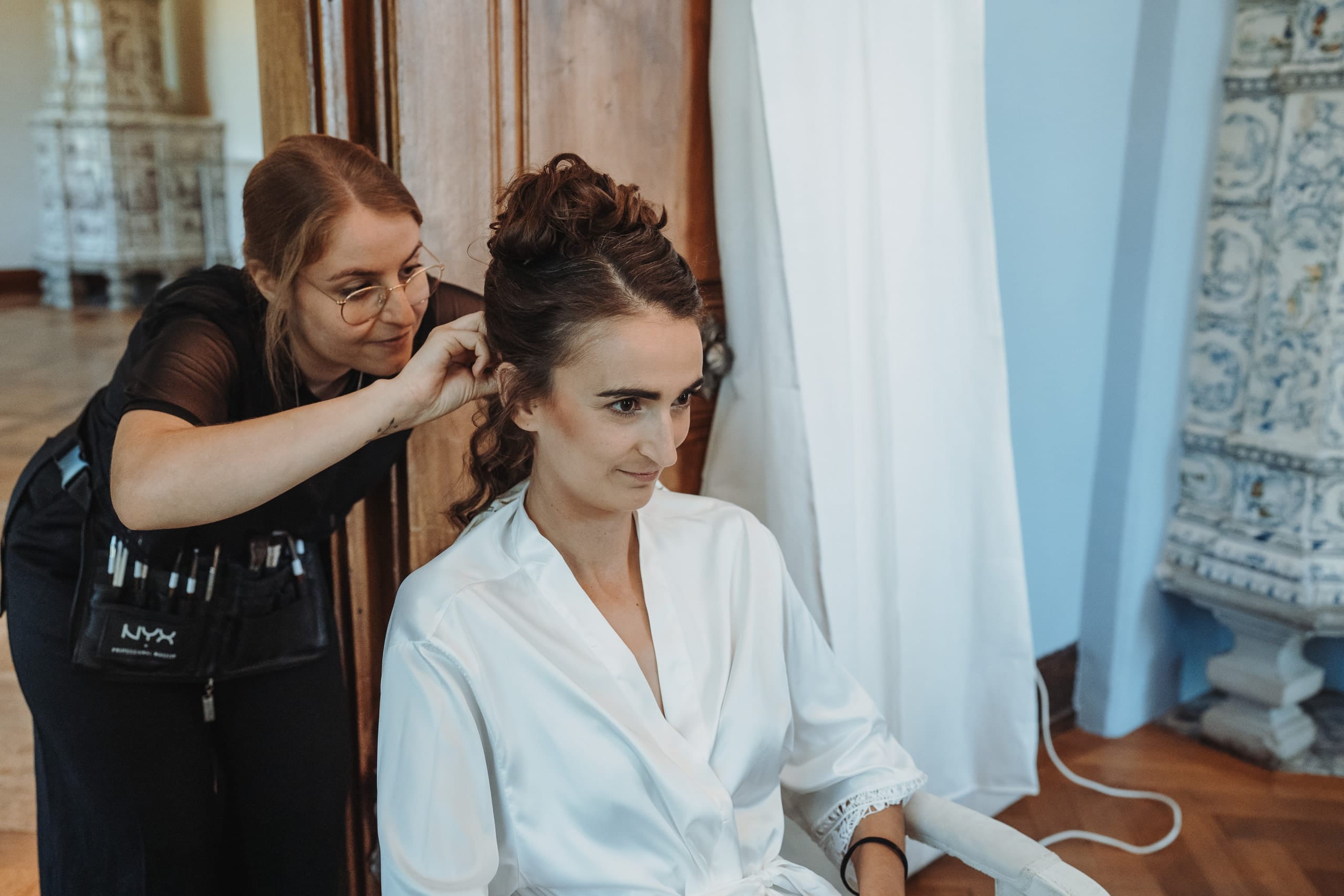 Die Coiffeuse steckt die Haare der Braut