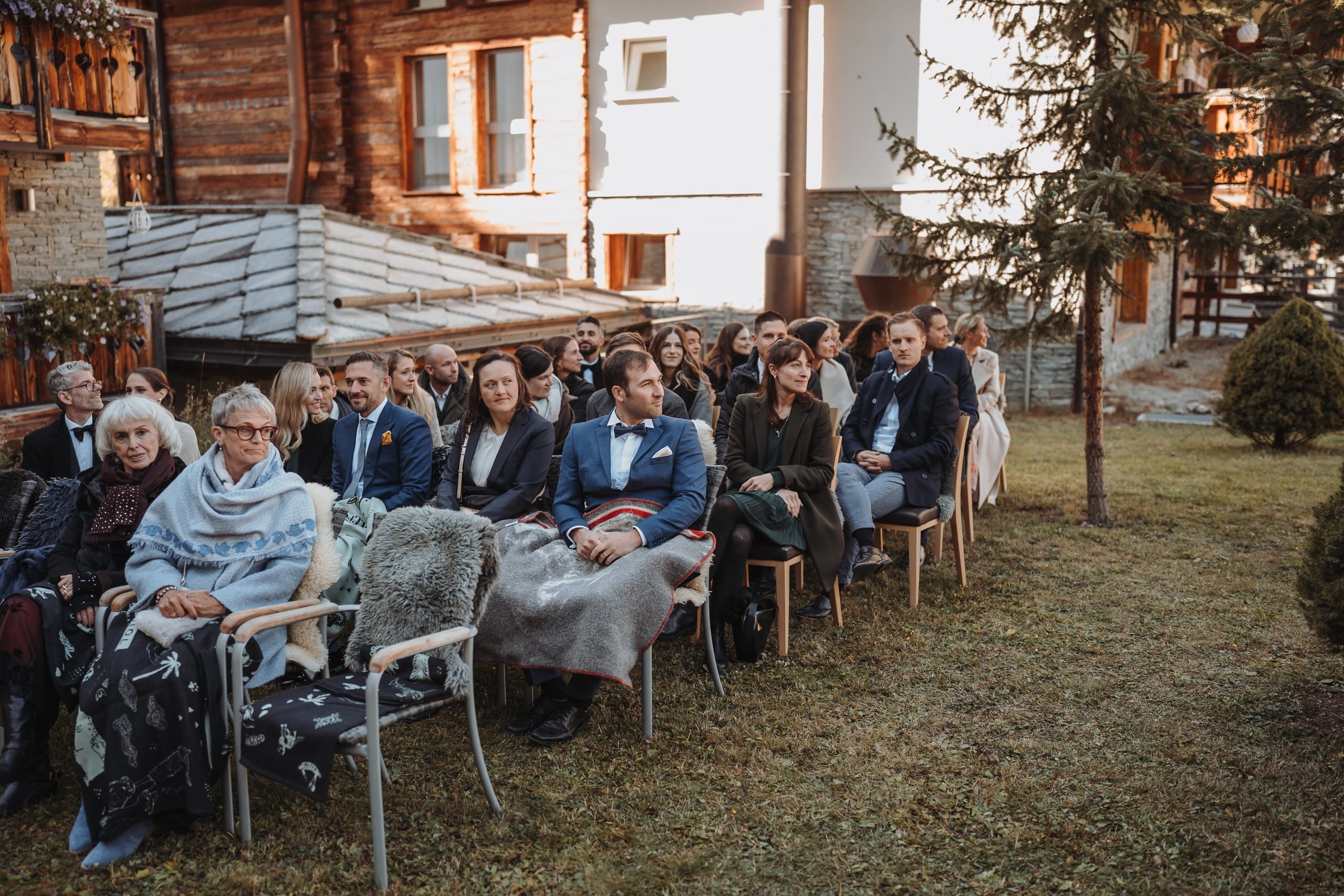 Die Gäste sitzen mit Decken und Fellen im Hotelgarten