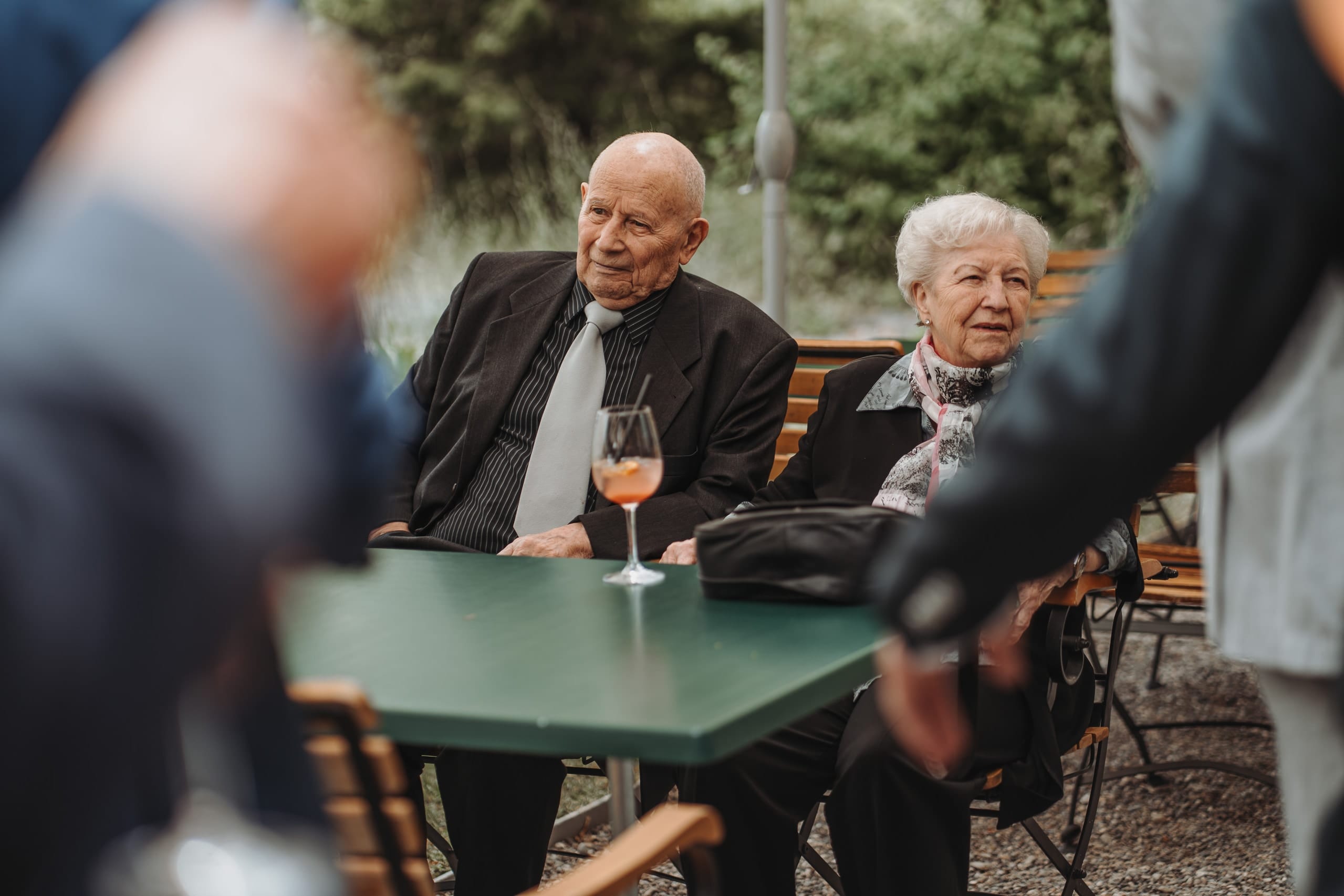 Ein älterer Mann und eine ältere Frau sitzen an einem Gartentisch