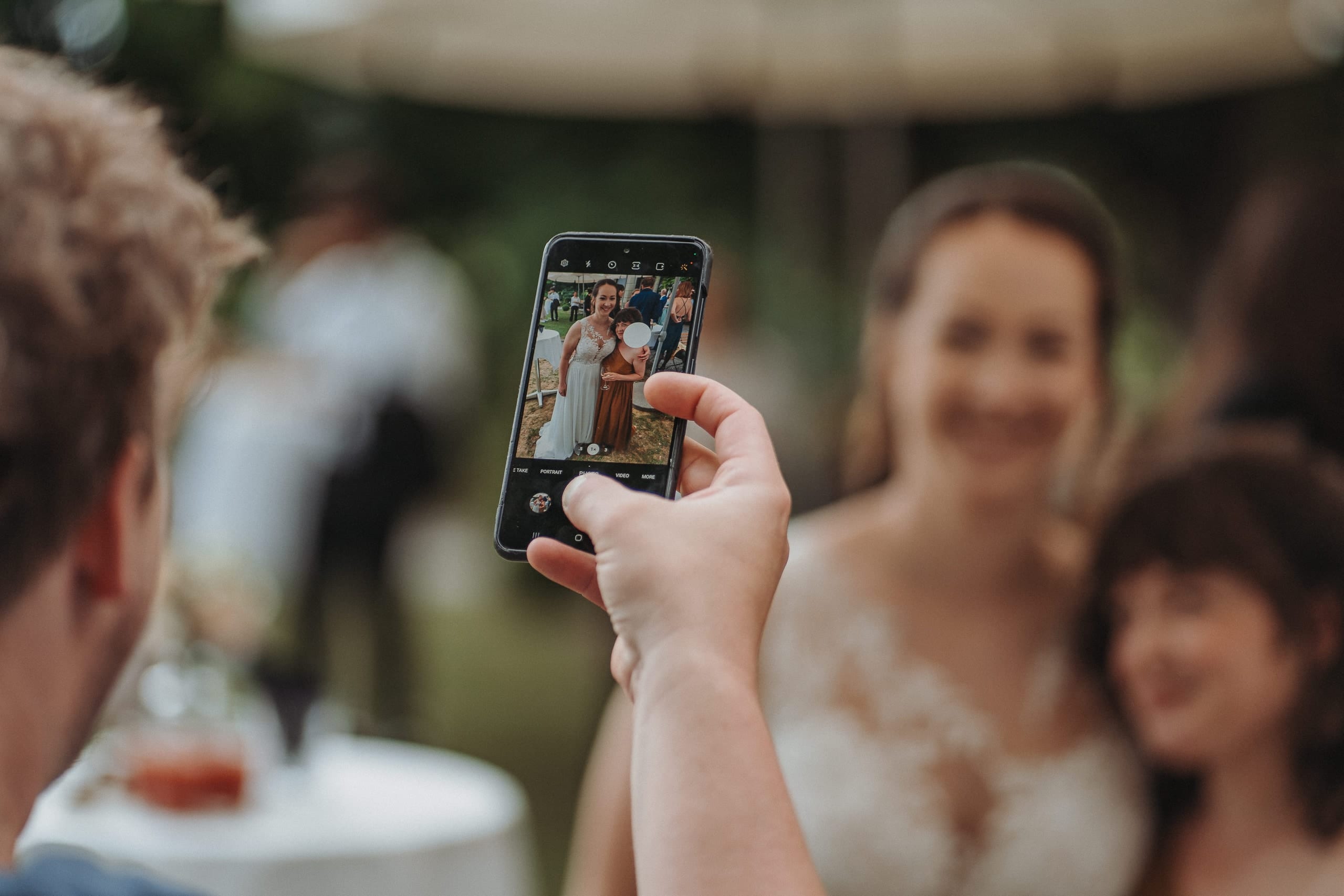 Ein Gast fotografiert die Braut mit dem Handy