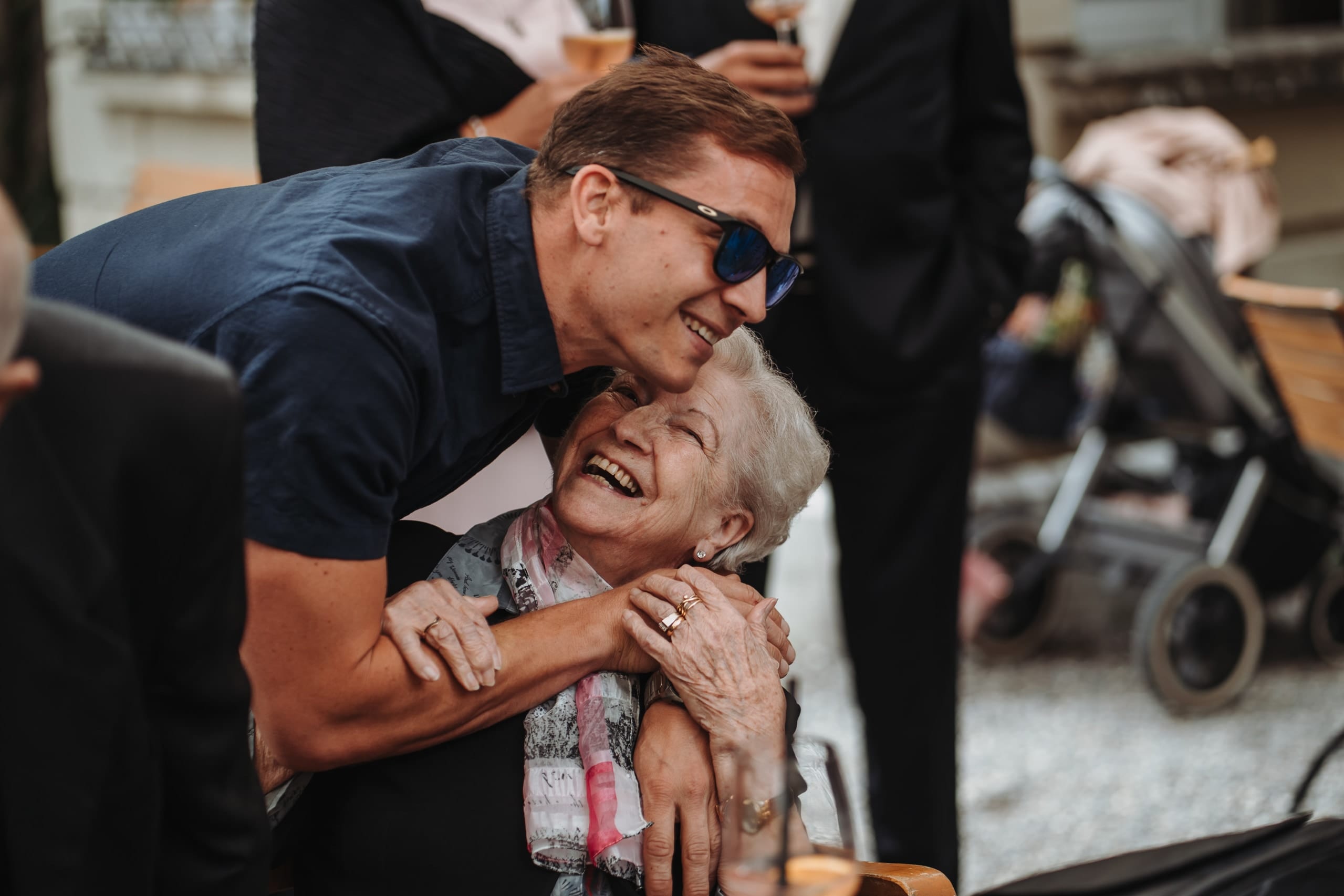 Ein Mann mit Sonnenbrille umarmt eine ältere Frau