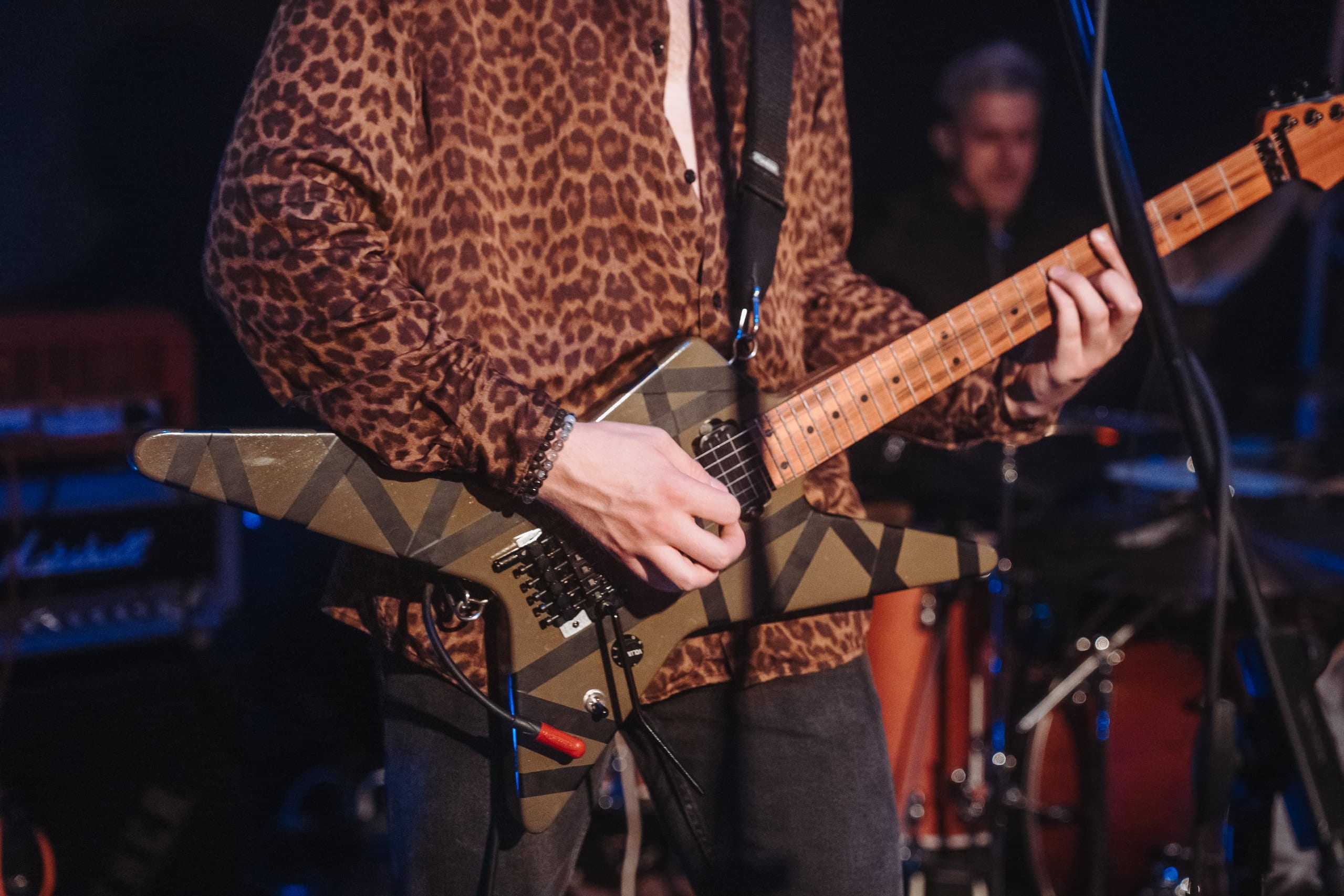 Ein Gitarrist im Leopardenhemd spielt eine gestreifte Gitarre in Sternform