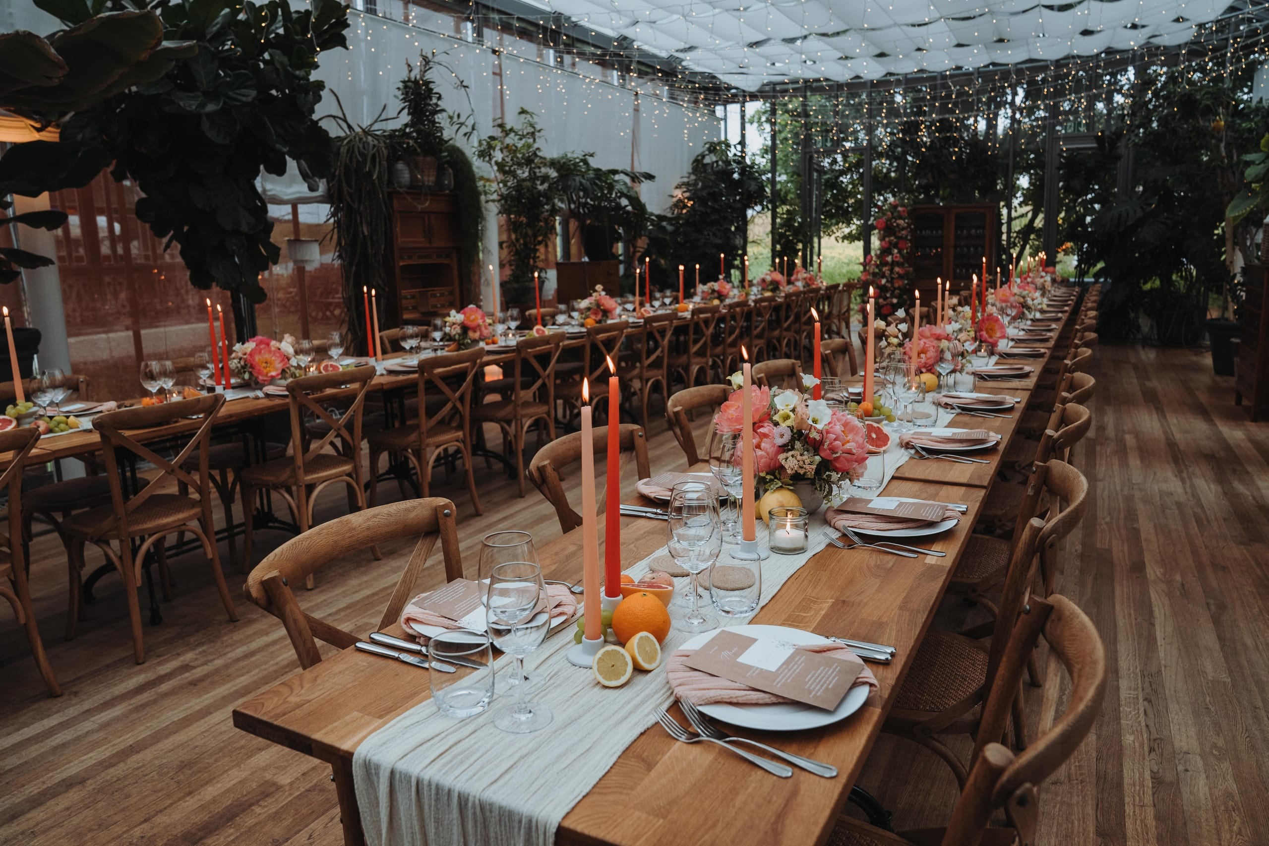 Hochzeitsdekoration: lange Tafel mit orangen Kerzen und Blumen