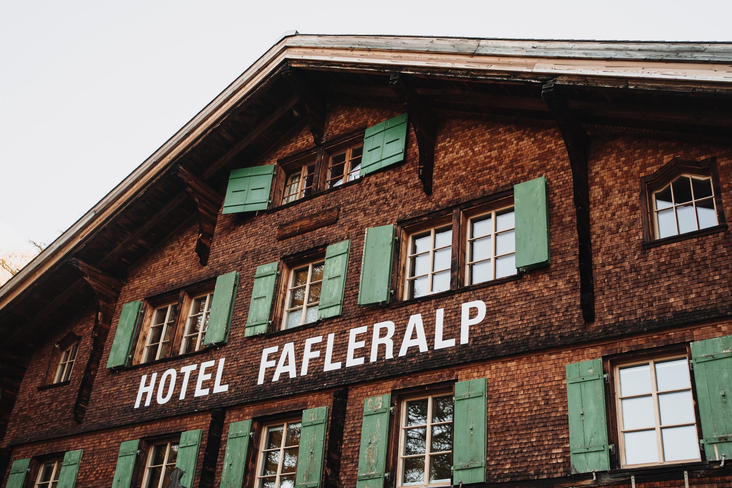 Die Holzfassade des Hotels Fafleralp mit grünen Fensterläden