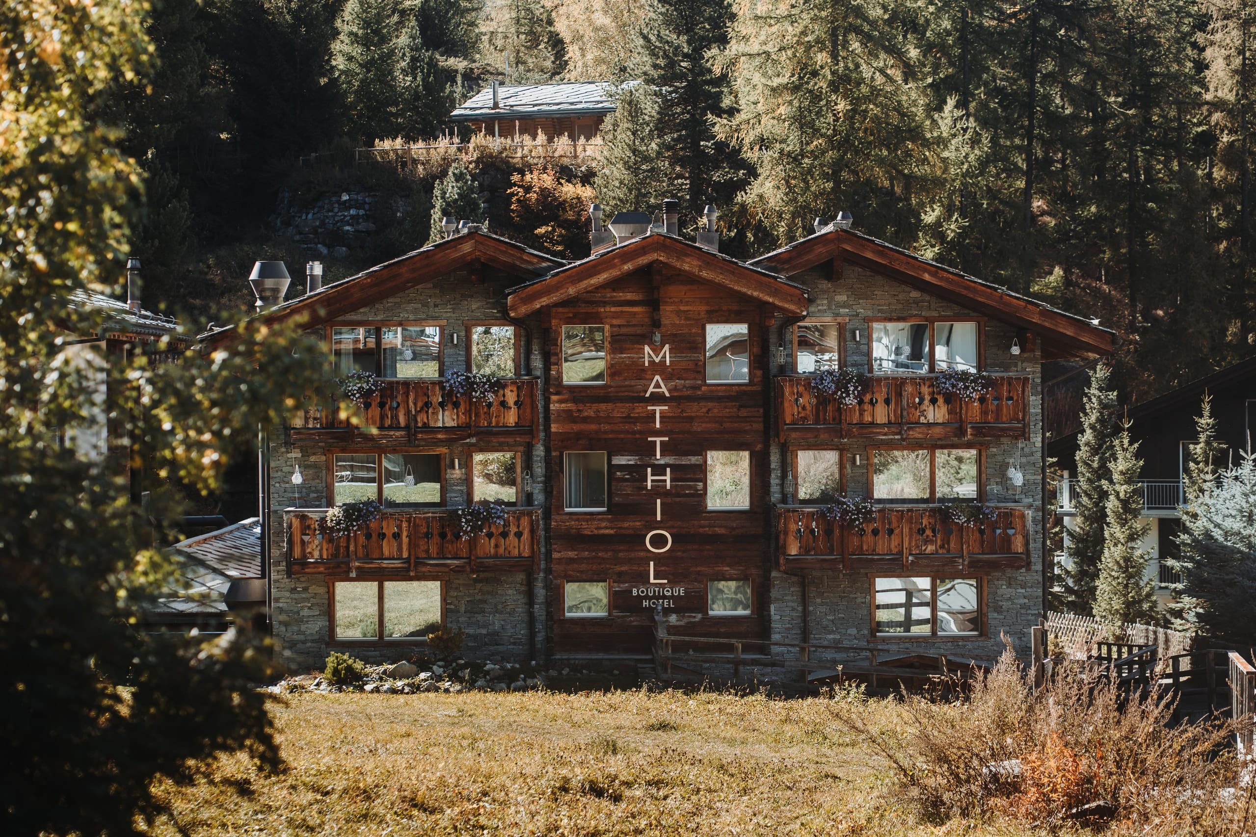 Das Boutique Hotel Matthiol in Zermatt mit Holzfassade und Blumenbalkonen