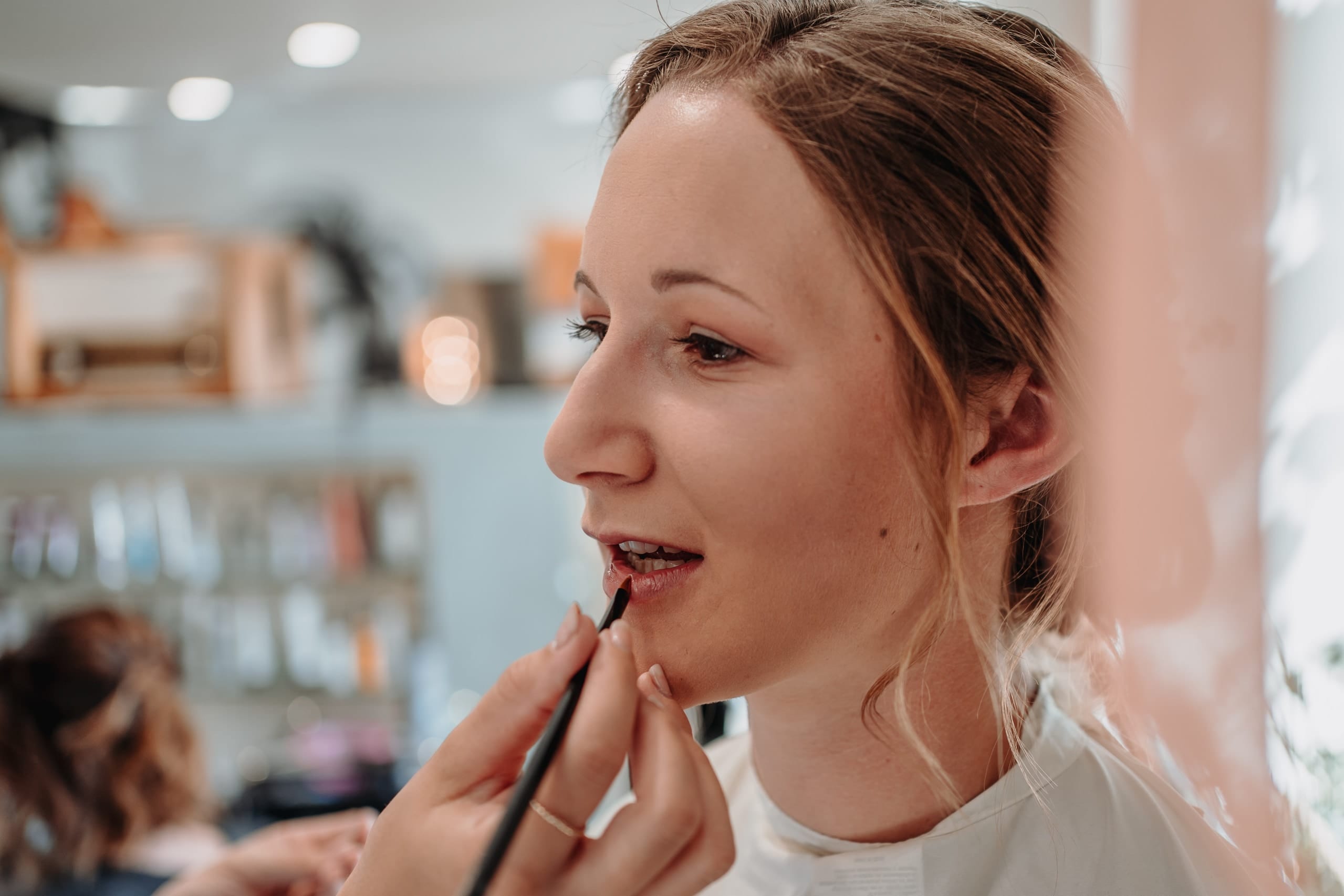 Lippenstift wird der Braut mit dem Pinsel aufgetragen