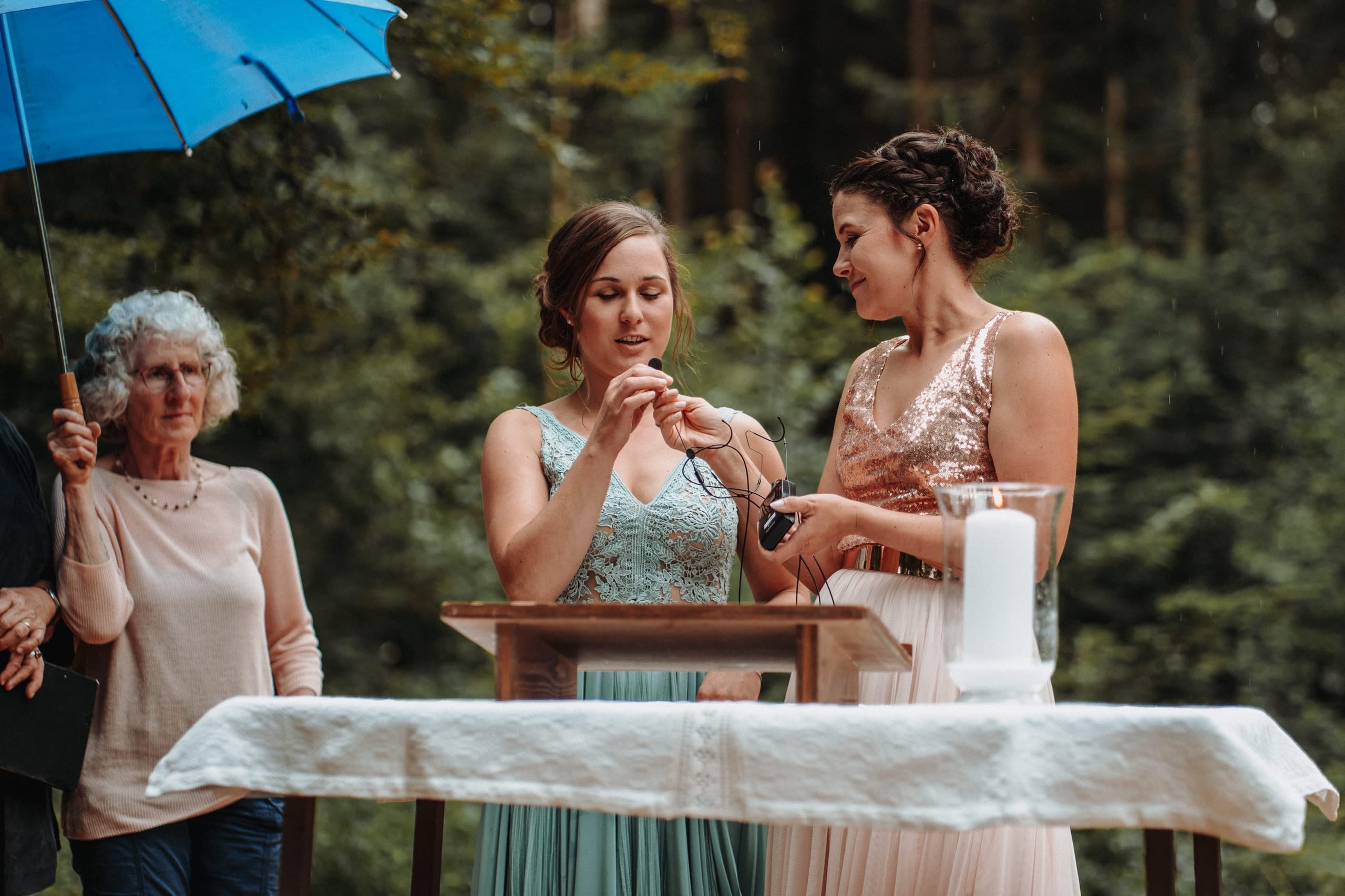 Zwei Frauen sprechen bei der Trauung, daneben hält eine Frau einen blauen Schirm
