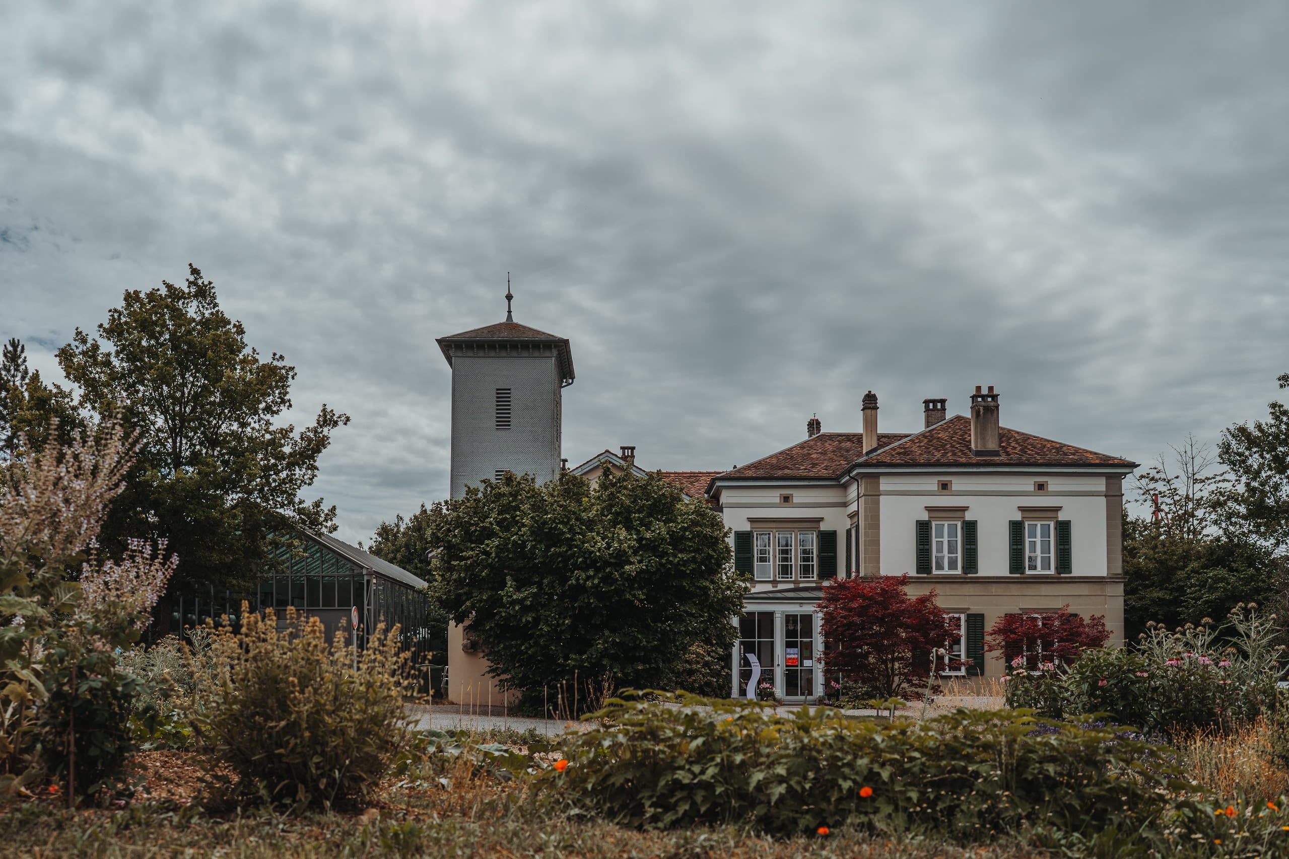 Das Landhaus des Schöngrün in Bern mit Turm, davor der Garten unter Wolken
