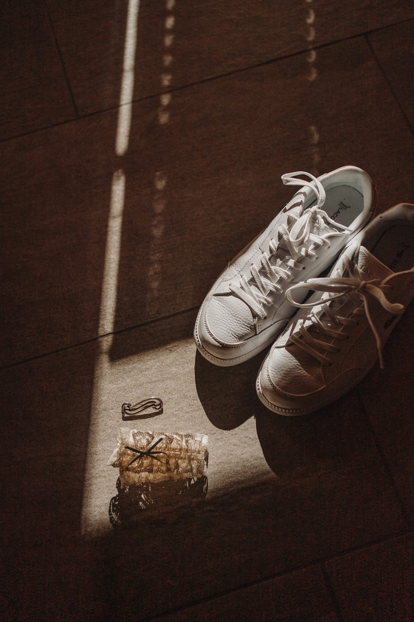 Weisse Sneaker im Lichtstreifen auf dem Holzboden