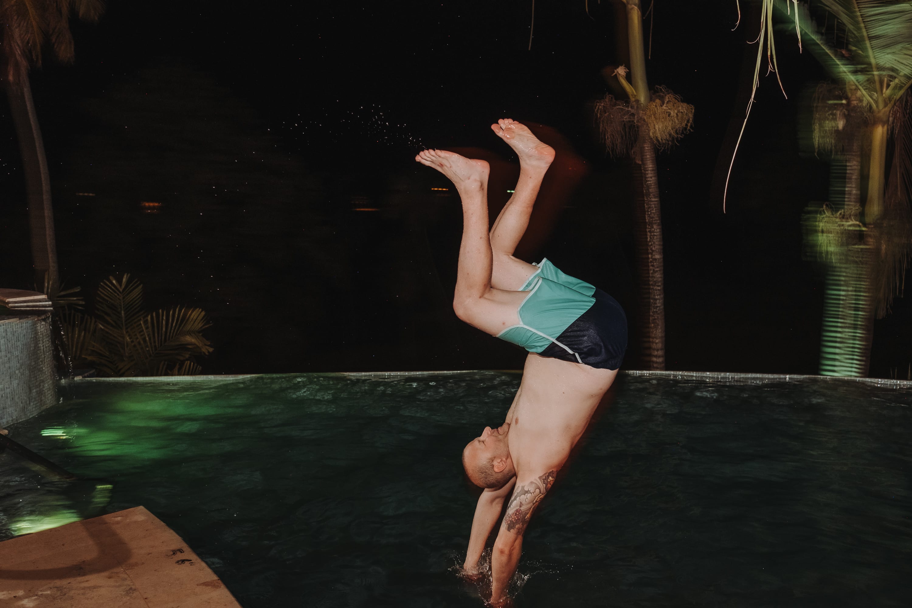 Ein Mann springt nachts kopfüber in den Pool der Villa Carpathia