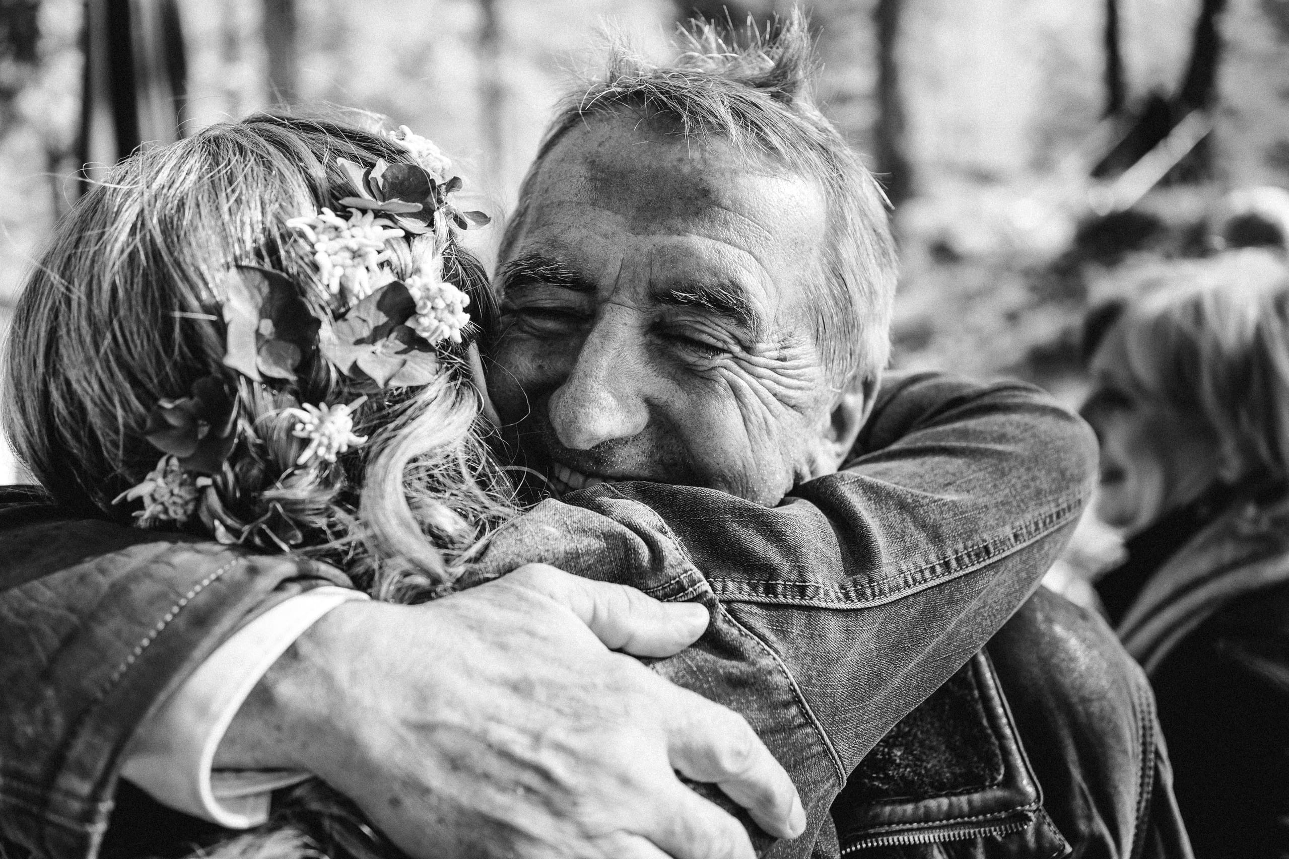 Schwarzweiss: Ein älterer Mann umarmt die Braut herzlich
