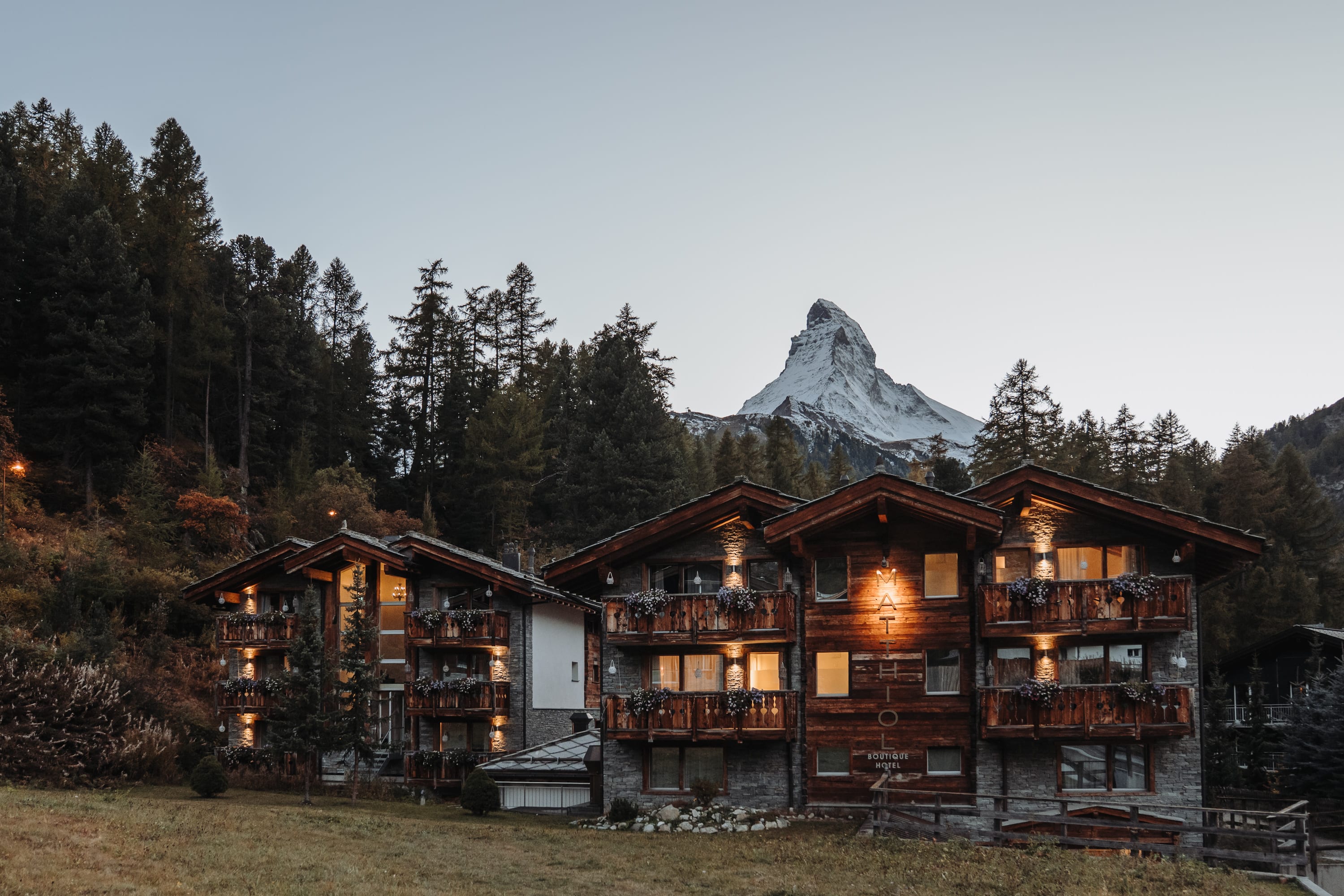 Beleuchtete Chalets in Zermatt in der Abenddämmerung, dahinter das Matterhorn