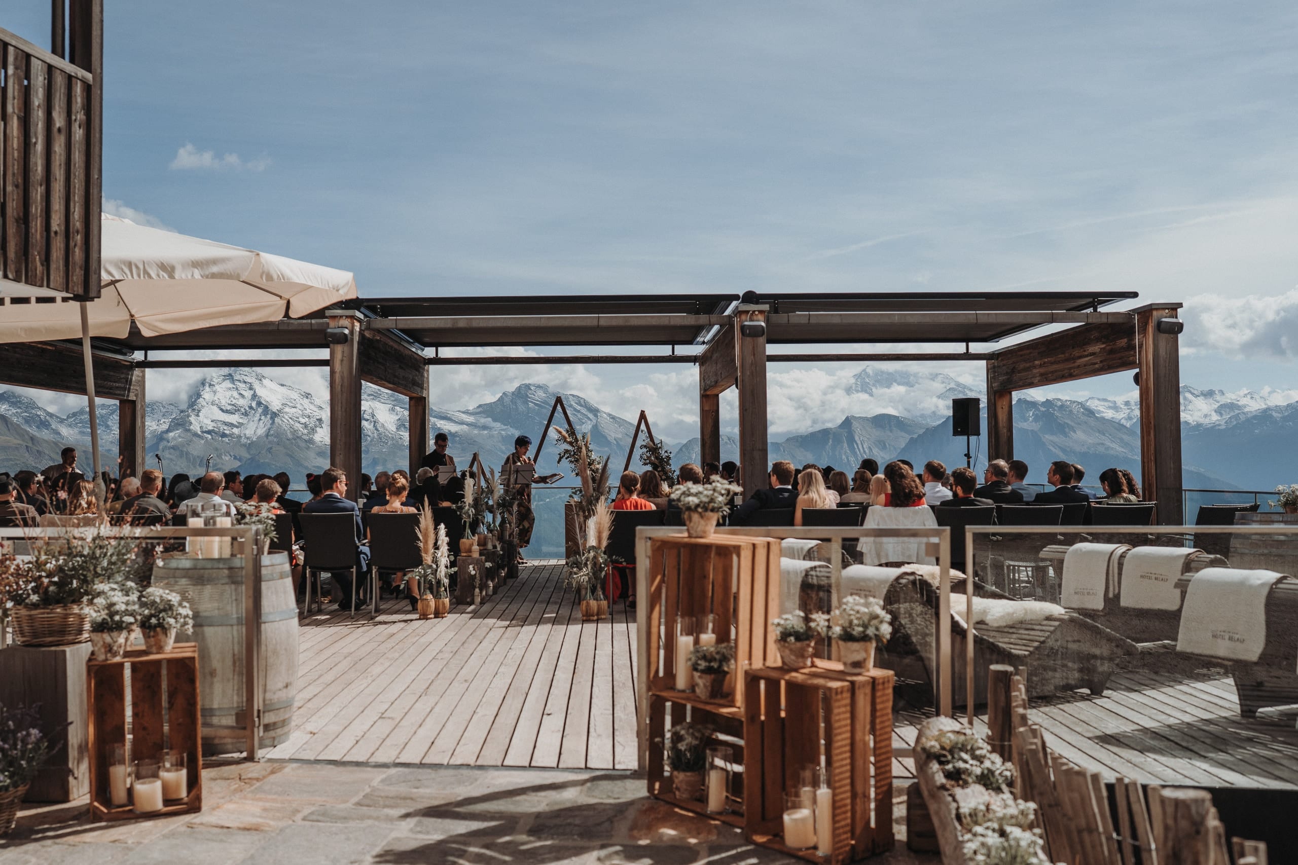Freie Trauung auf einer Holzterrasse auf der Belalp, die Gäste blicken auf verschneite Gipfel