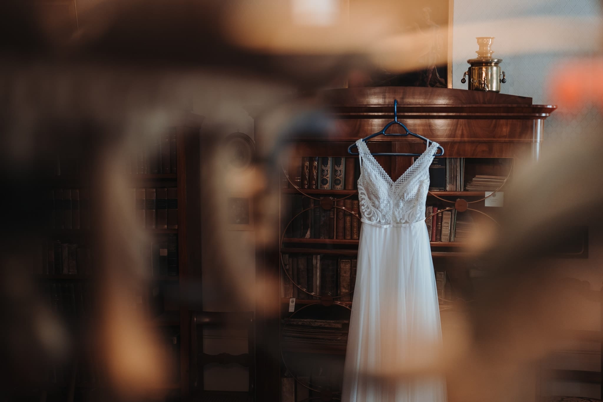 Das Brautkleid hängt in einem Raum mit alten Bücherregalen