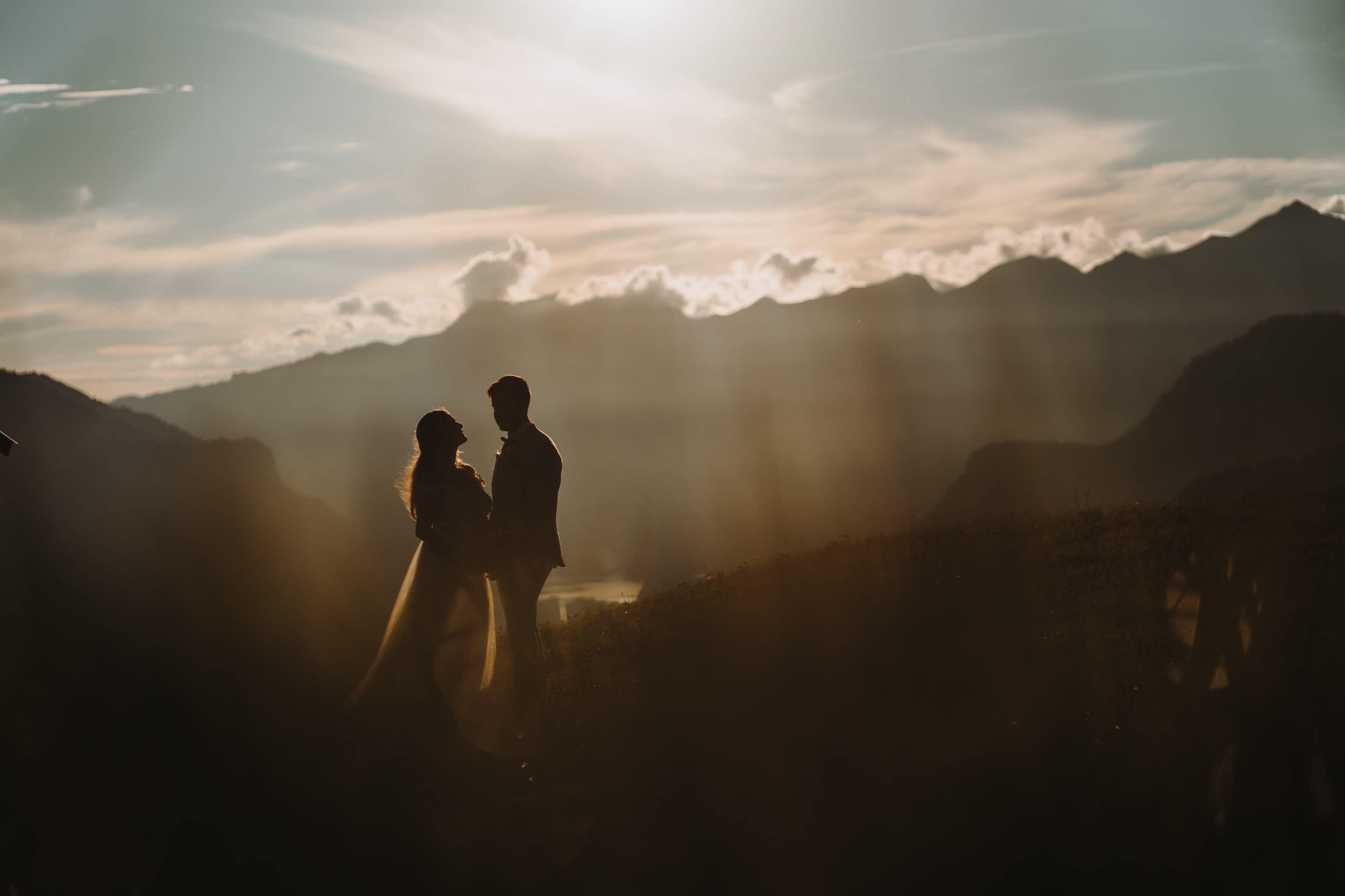 Das Brautpaar als Silhouette im warmen Abendlicht am Hasliberg, dahinter die Berge