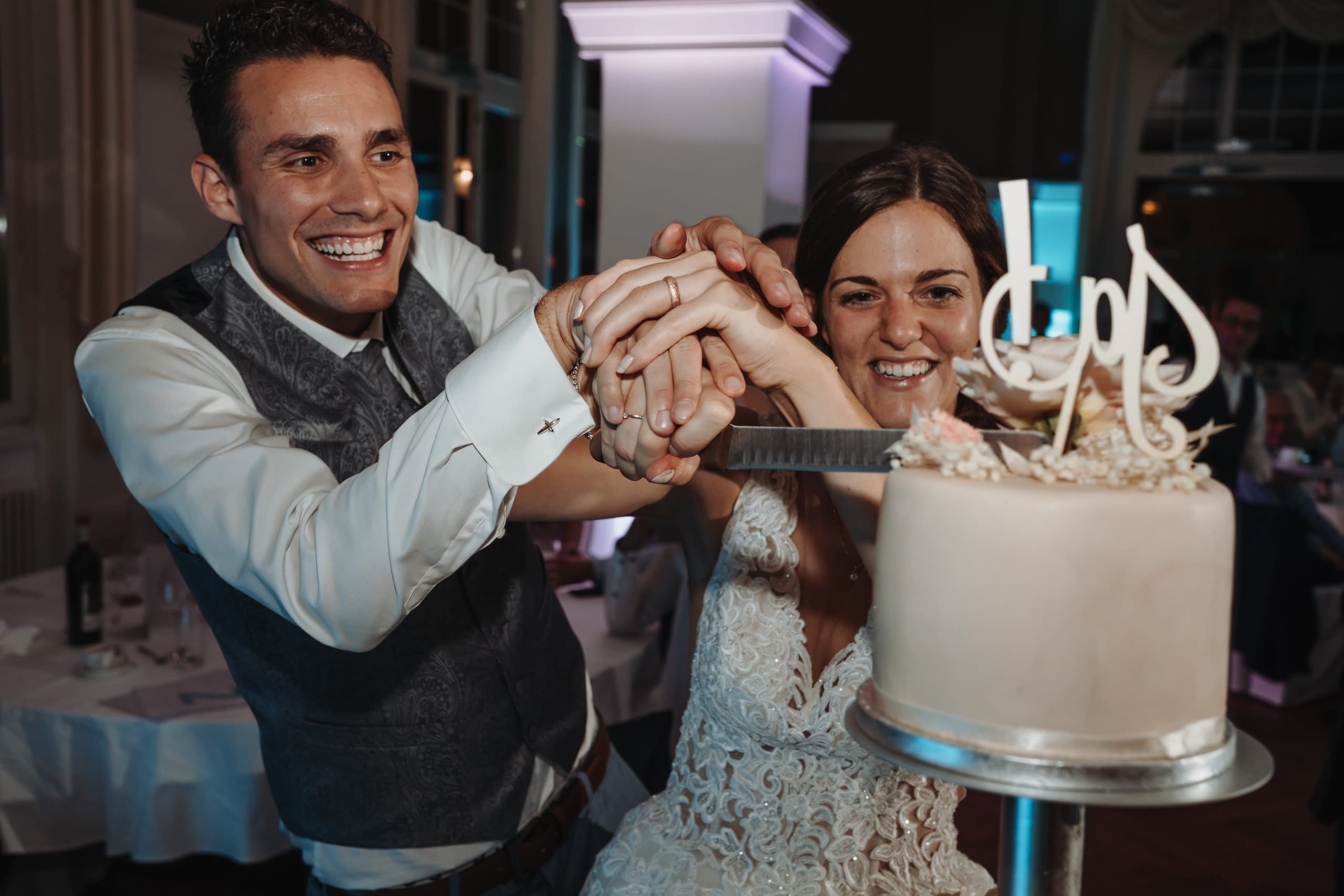 Das Brautpaar schneidet lachend die Hochzeitstorte an