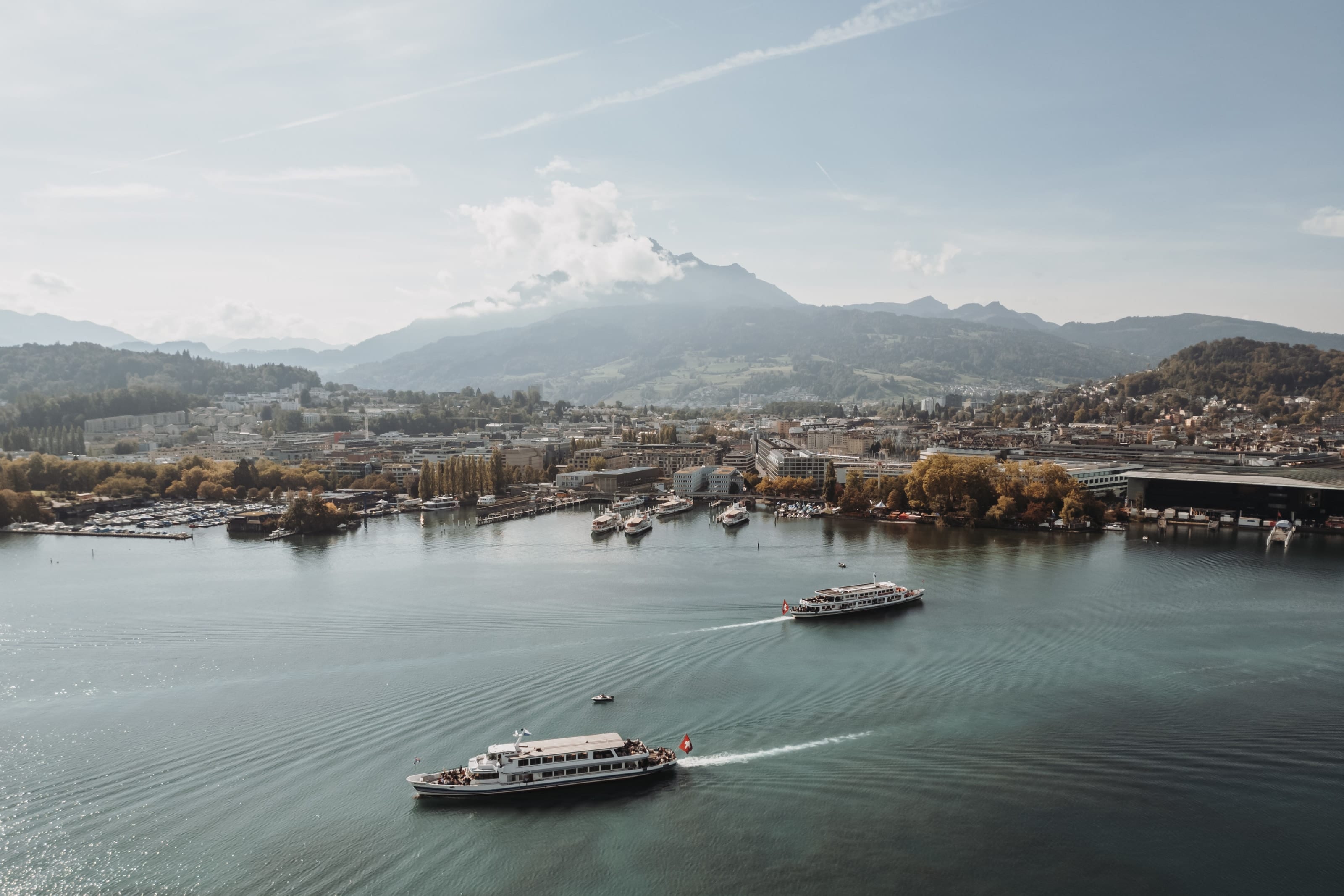 Luzern und der Vierwaldstättersee von oben, auf dem See fahren Schiffe, dahinter die Berge